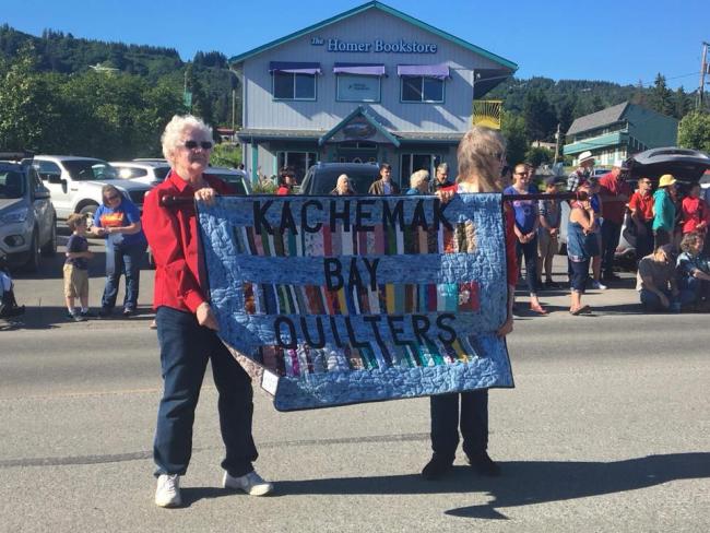 Glenda and Marali holding the Kachemak Bay Quilters sign in the 4th of July parade