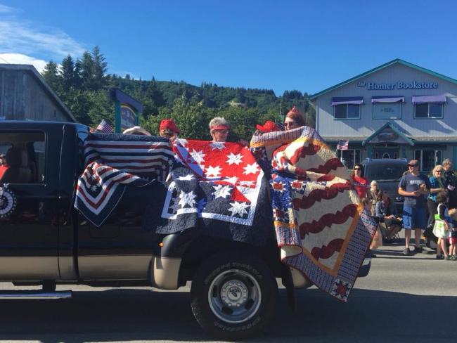 Margaret, Elaine, and Shirley holding their Quilts of Valor up in the 4th of July parade