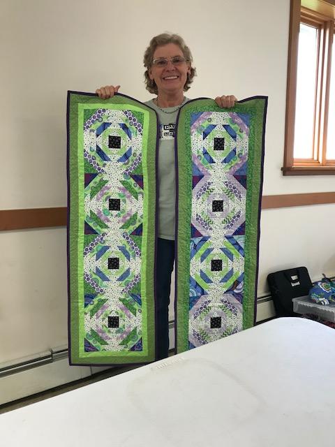 Janet holding up her pineapple quilts from the class from Jean Ann Wright